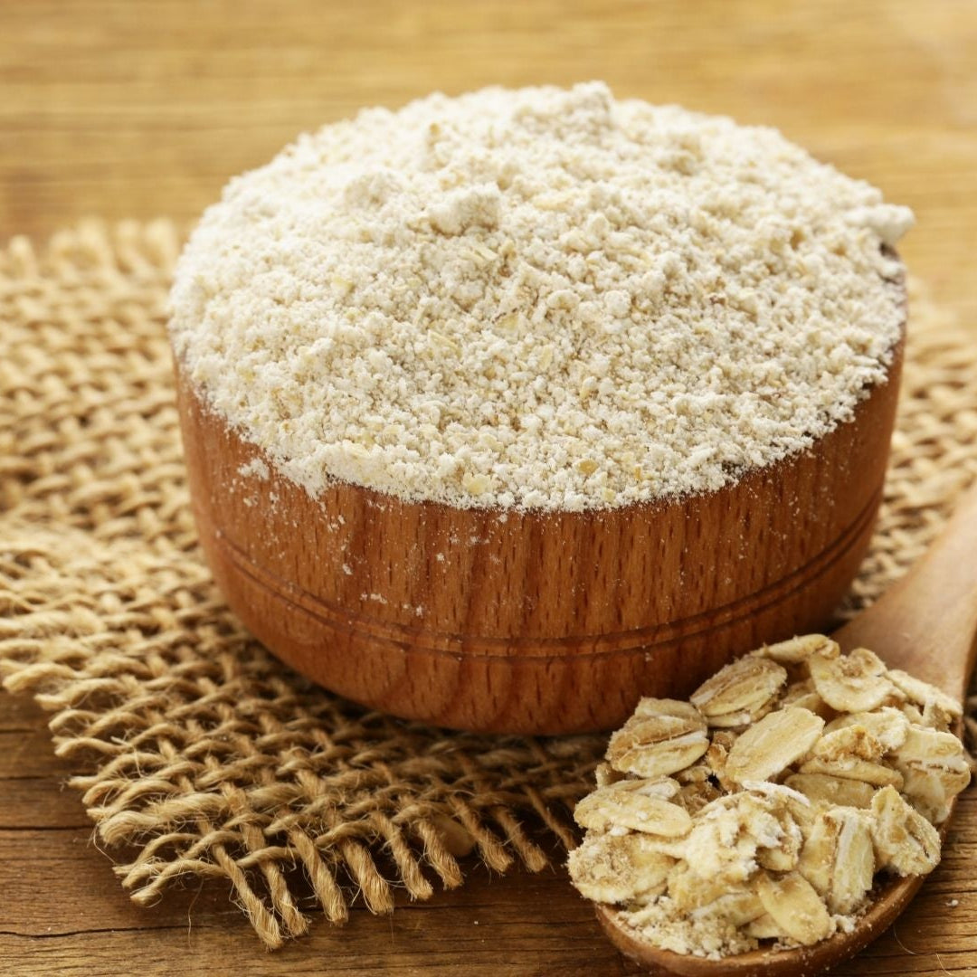 Wooden bowl filled with oat flour on a wooden surface