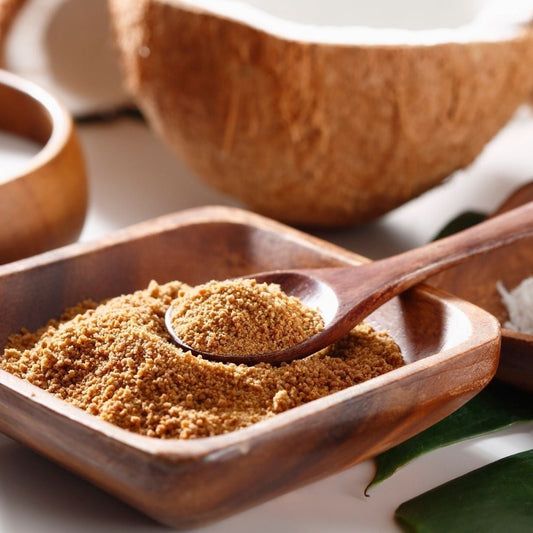 Wooden bowl with ground spice, wooden spoon, and coconuts on a light background